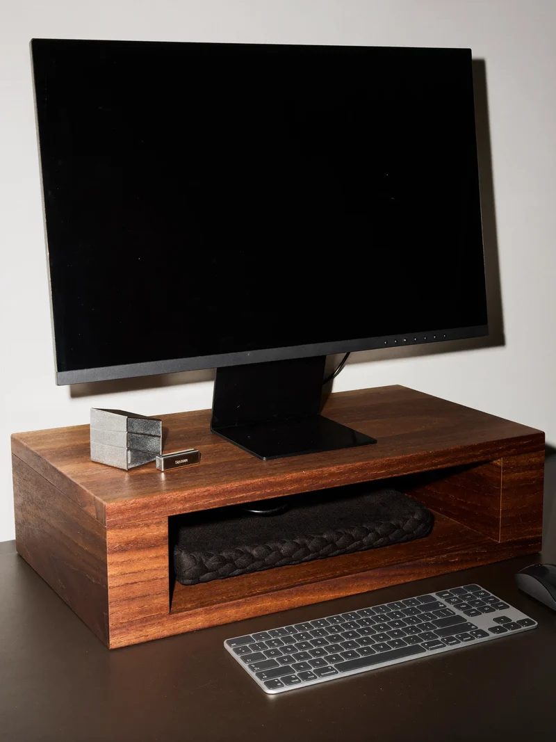 Holzerhöhung mit geflochtenem Kabelfach unter Monitor und Tastatur, Illustration
